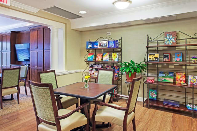 A cozy indoor seating area with a table, chairs, and bookshelves filled with colorful books.