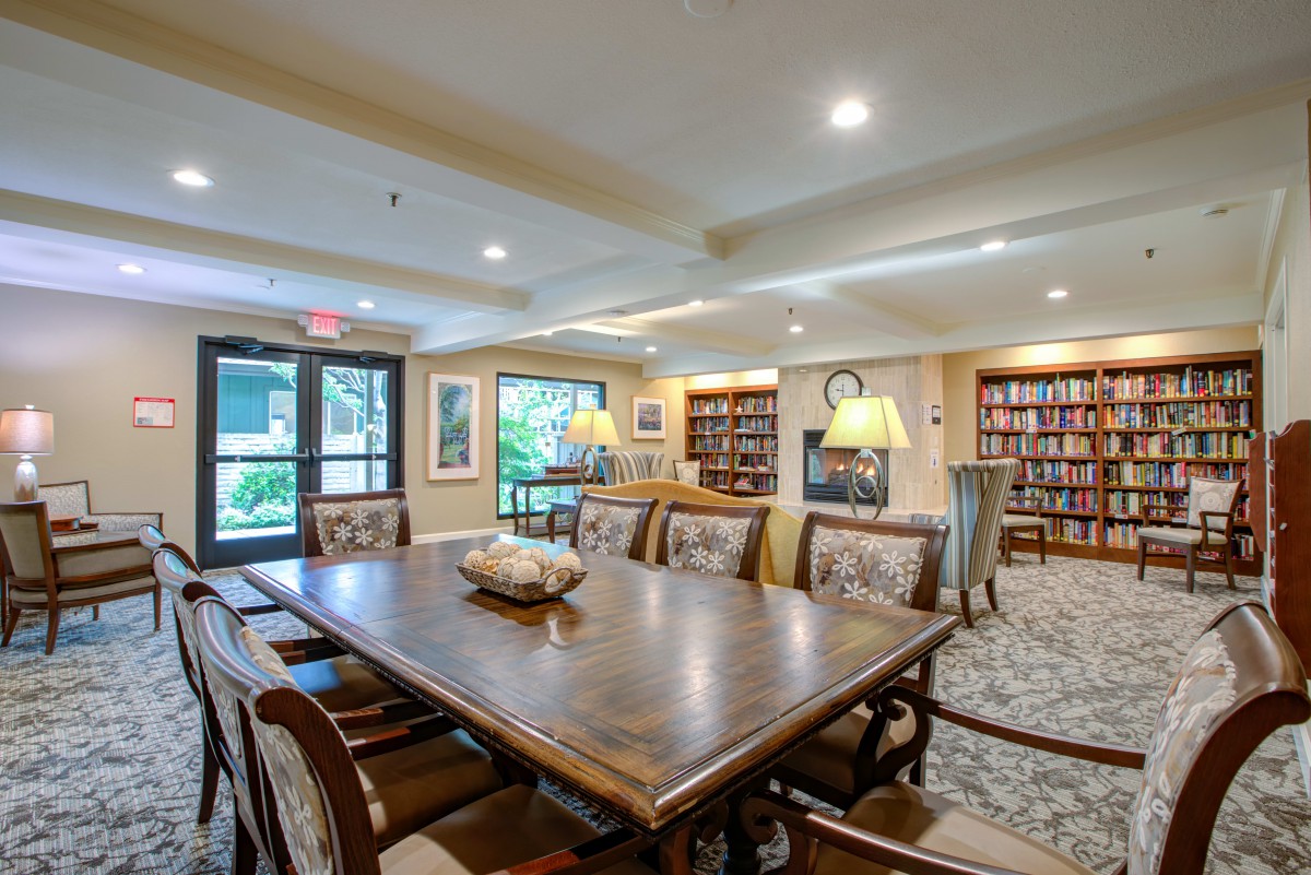 A cozy library with a large table and bookshelves filled with books.