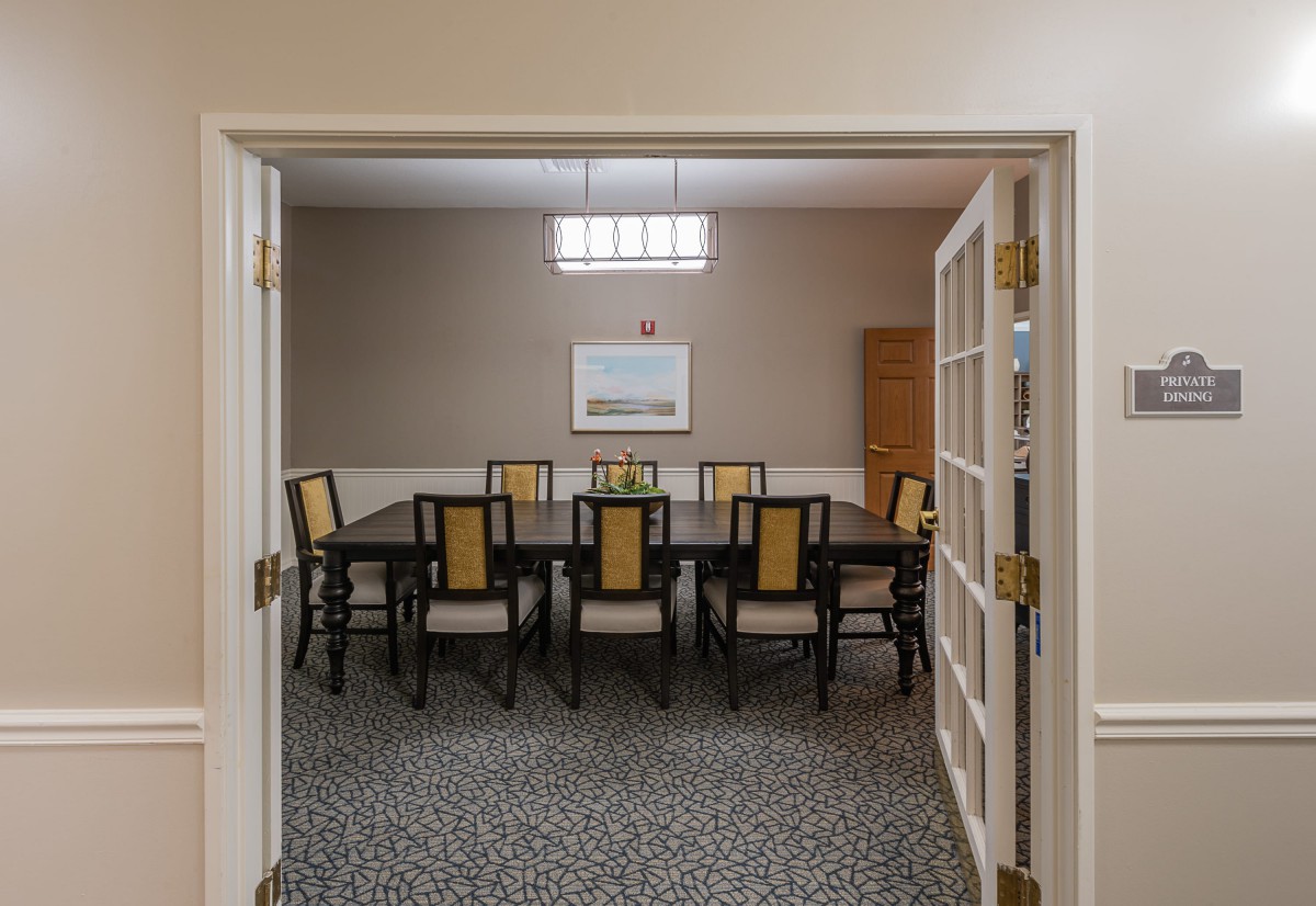A well-lit dining or conference room with a large table and several chairs, decorated in a neutral color scheme.