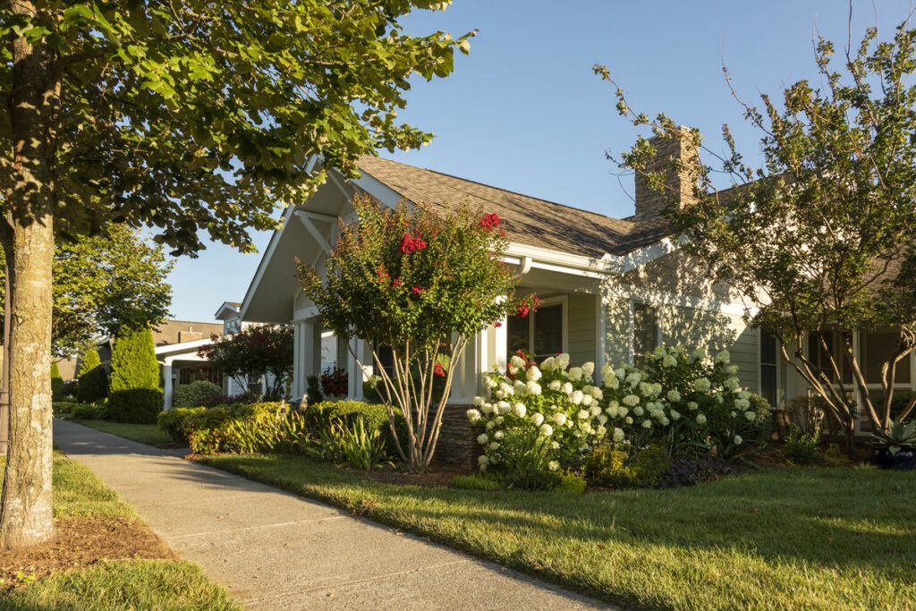 A charming suburban house surrounded by a well-maintained garden and trees.