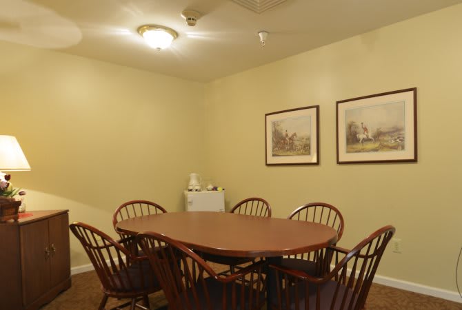 A small conference room with a wooden meeting table and chairs, decorated with framed artwork on the walls.