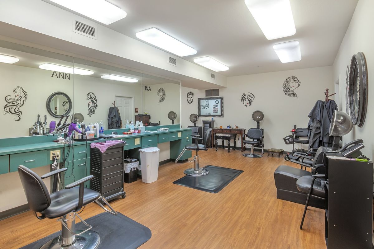 A spacious hair salon interior with multiple styling stations and wood flooring.