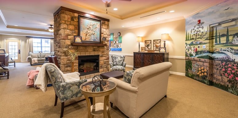 A warmly lit living room featuring a stone fireplace, comfortable sofas, and elegant home decor.