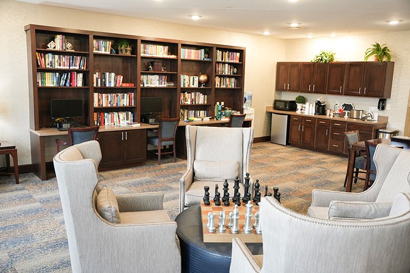 A cozy library room with bookshelves, a chessboard, and comfortable seating.