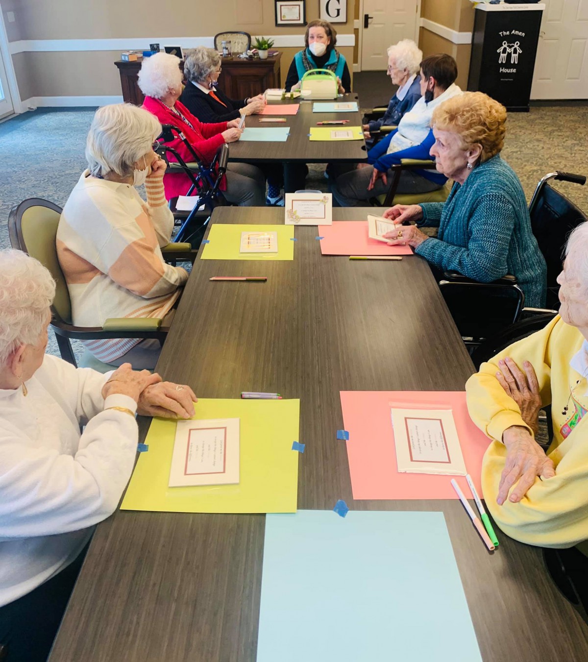 A group of seniors sitting around tables engaged in a planned activity.