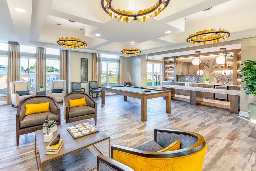 A stylish and modern lounge area featuring comfortable seating, a pool table, and a kitchen space with elegant lighting.