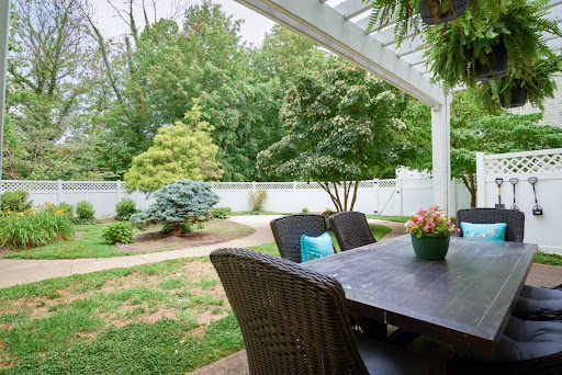 A serene outdoor patio with a table surrounded by lush greenery.