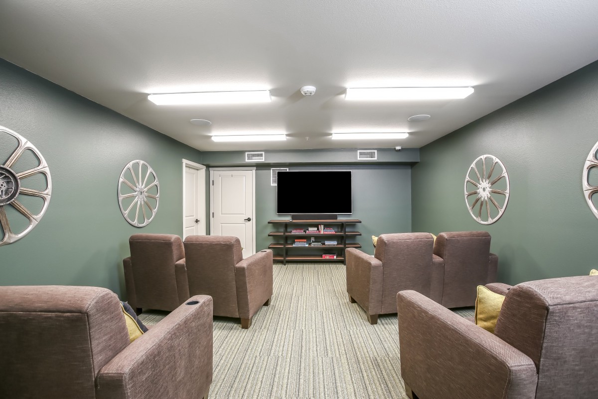 A cozy home theater room with armchairs, a large television, and ambient lighting.