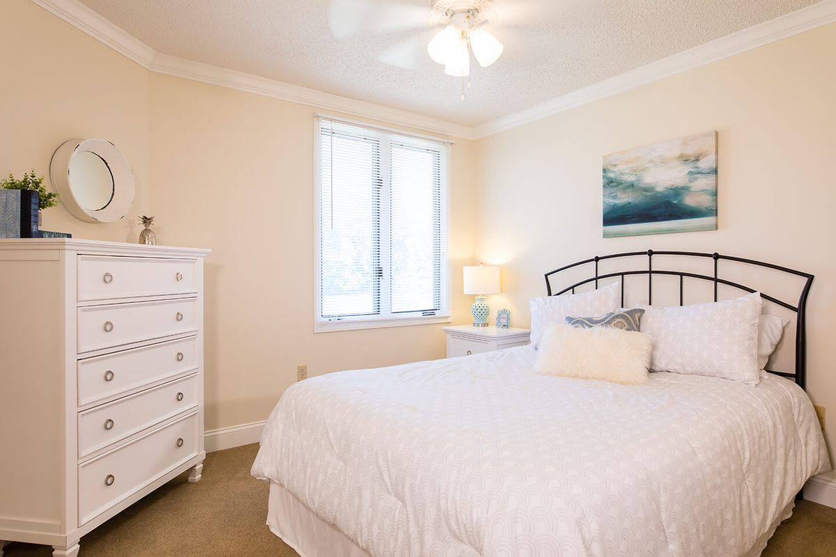 A bright bedroom with white furnishings and decor.