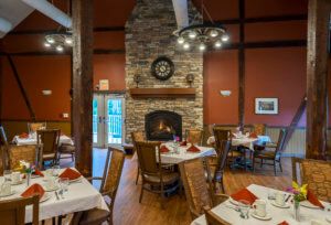 A cozy restaurant dining area with neatly set tables and a stone fireplace.