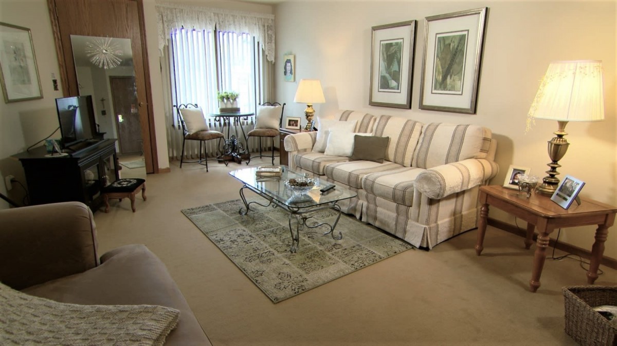A cozy living room with a striped sofa, glass coffee table, and elegant decor.