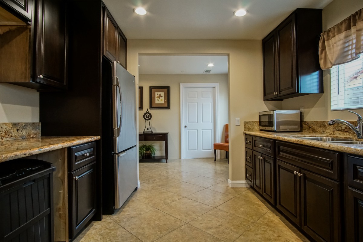 A modern kitchen with dark cabinets and stainless steel appliances.