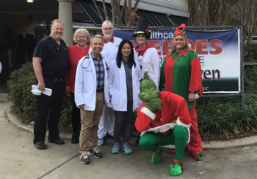 A festive gathering of healthcare professionals and the Grinch at a community holiday event.
