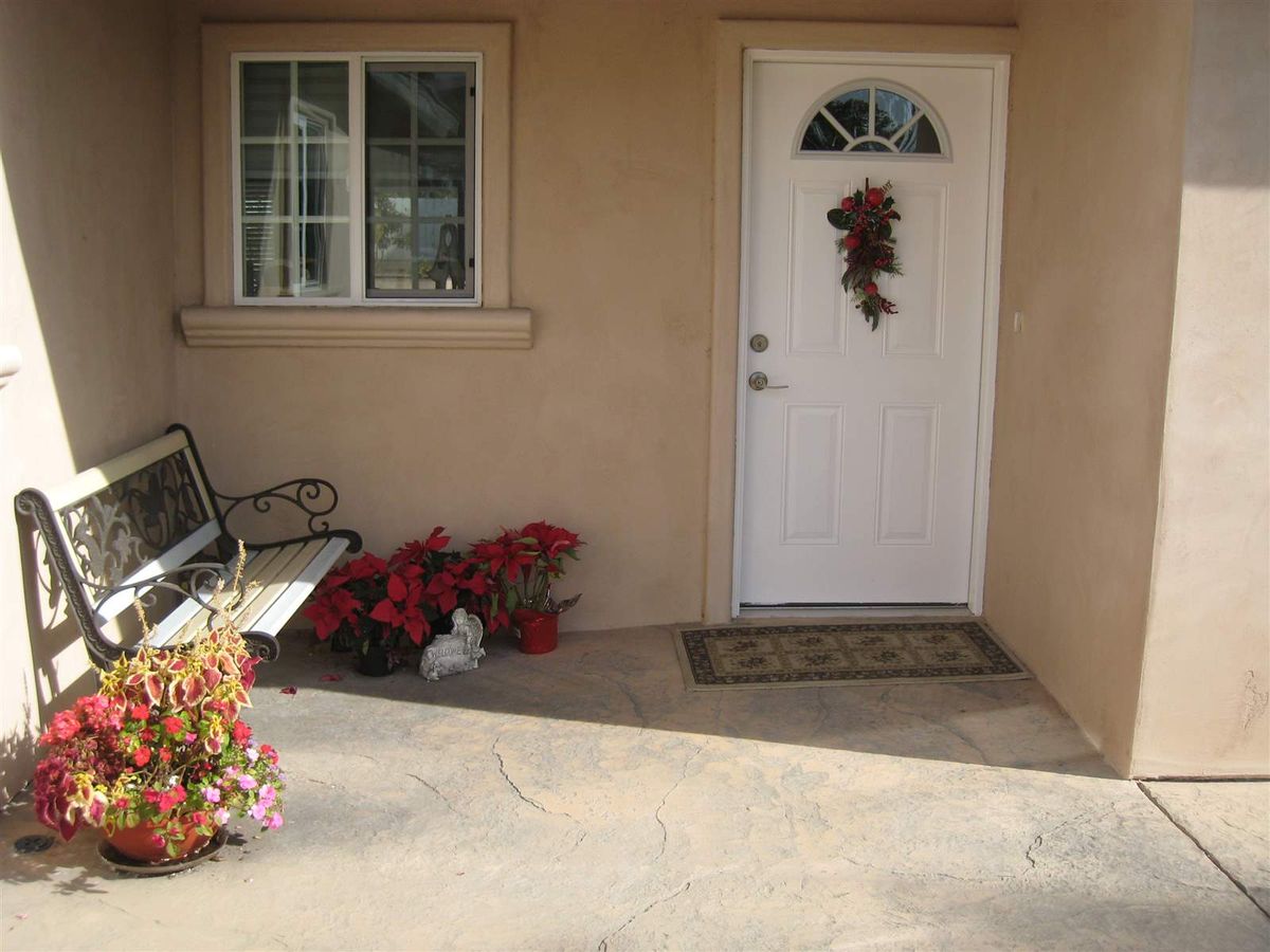 A cozy front porch with a white door adorned with seasonal decor, a bench, and potted plants.