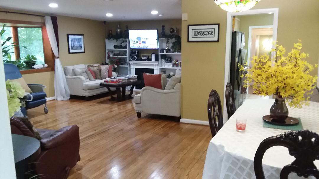 A cozy living room with a dining area featuring hardwood floors, sofas, and a television.