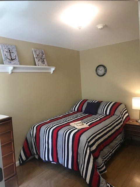 A cozy bedroom with a striped bedspread, a nightstand with a lamp, and wall decor.