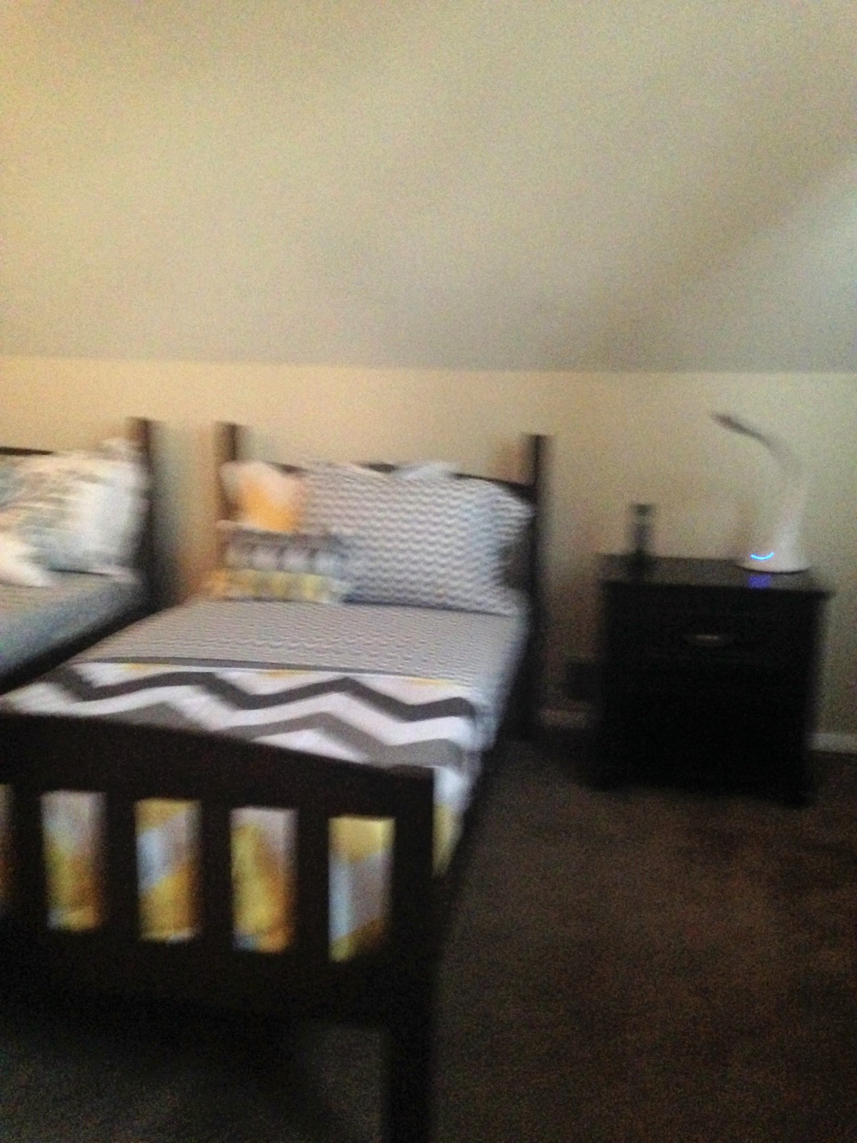 A cozy bedroom featuring twin beds with striped bedding and a nightstand with a lamp.