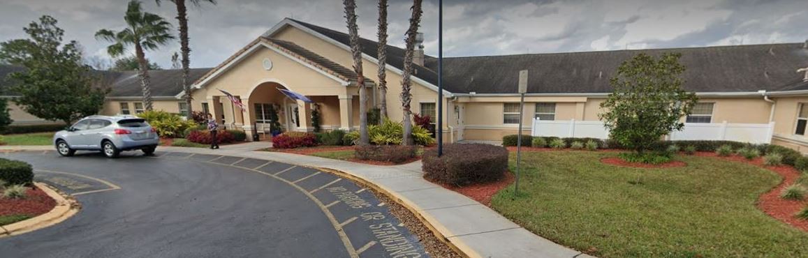 Front view of a building entrance with landscaping and palm trees.