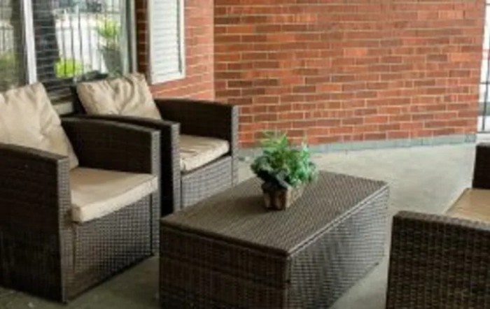 A cozy outdoor patio setup with wicker furniture and a potted plant.