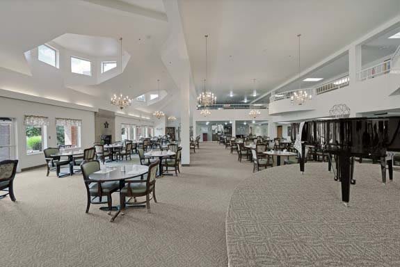 A spacious dining hall with elegant chandeliers and neatly arranged tables and chairs.