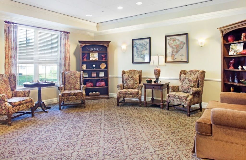 A cozy lobby with traditional decor, featuring armchairs and a bookshelf.
