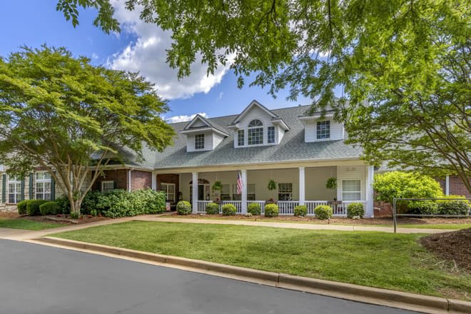 A charming suburban house with a well-maintained lawn and surrounding trees.