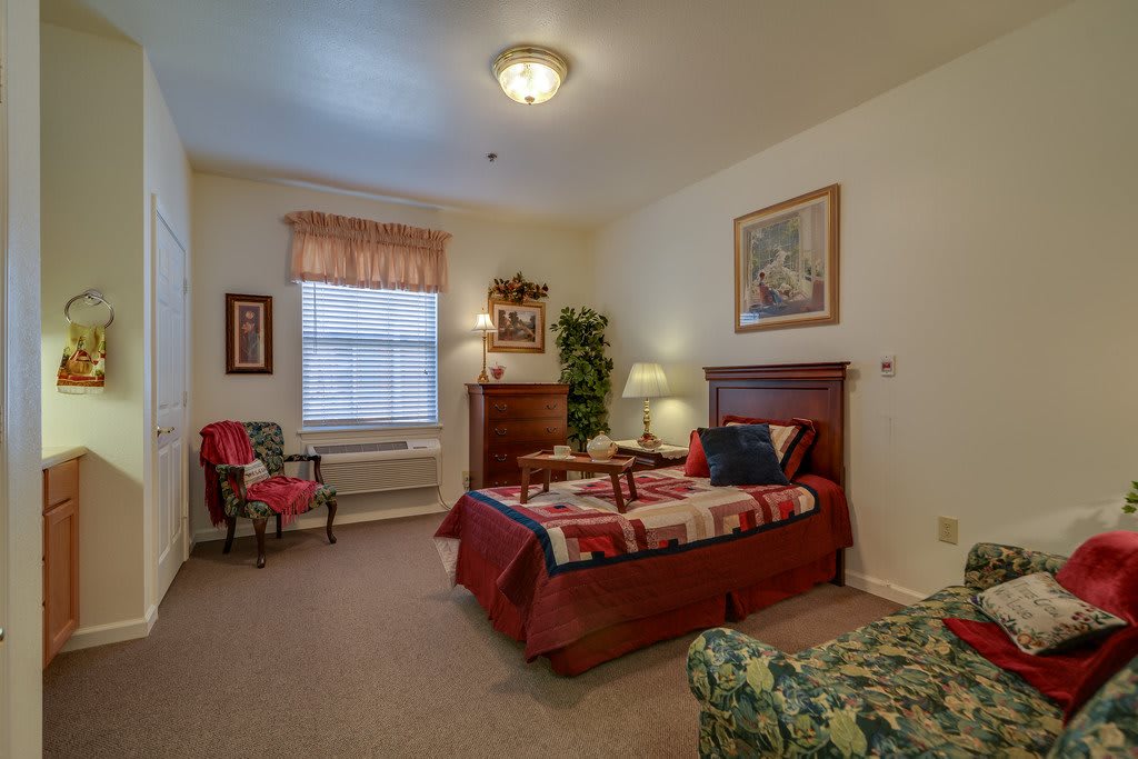 A cozy bedroom with a bed, chair, and decorative elements.
