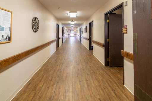 A well-lit corridor featuring wooden laminate flooring and multiple doors along the sides.