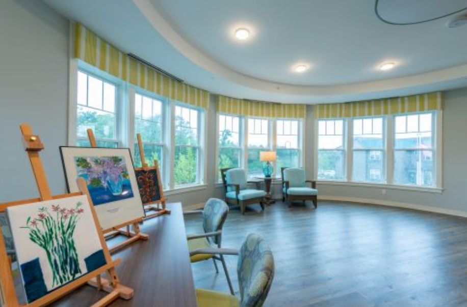 A bright art room with large windows, featuring easels and comfortable seating.