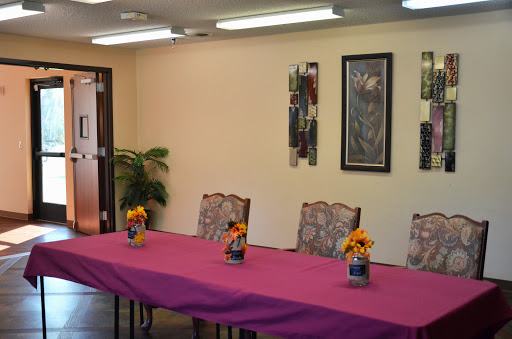 A well-arranged meeting room featuring a pink tablecloth, decorative flowers, and stylish furniture.