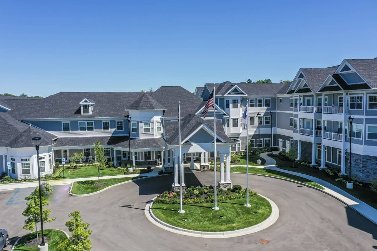 A large residential building with landscaped grounds and flags at the entrance.