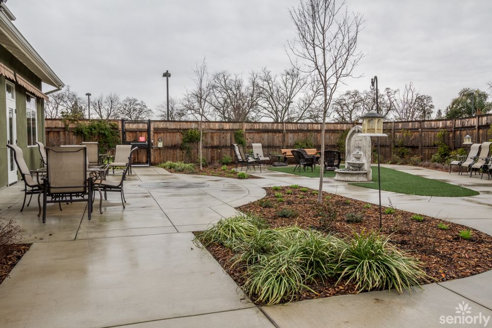 A well-maintained outdoor patio area with garden furniture, a walkway, and landscaping.