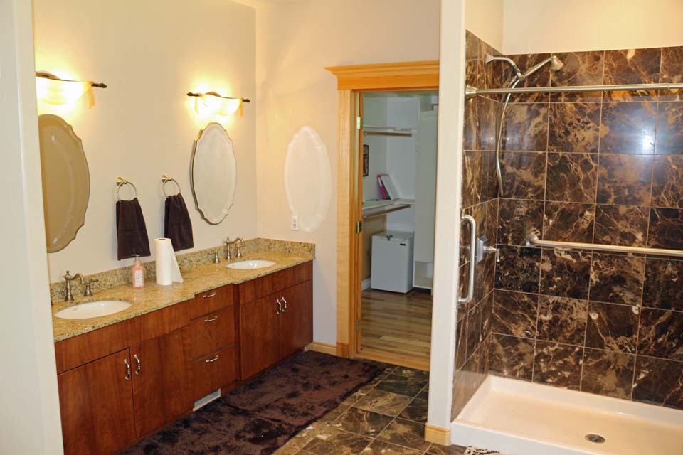 A modern bathroom featuring a double sink vanity and a marble-tiled shower.