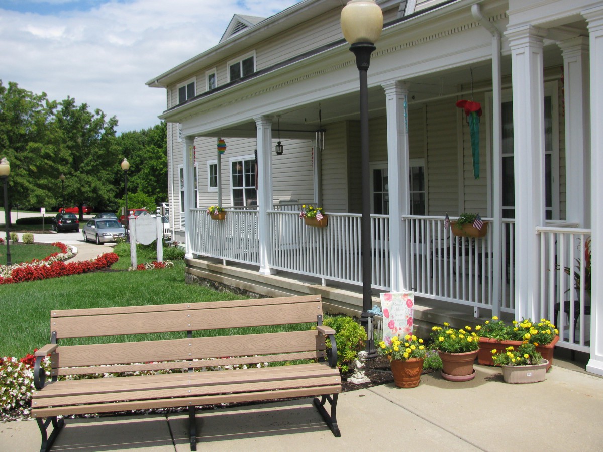 A charming porch with flower pots and a nearby bench under a clear sky.