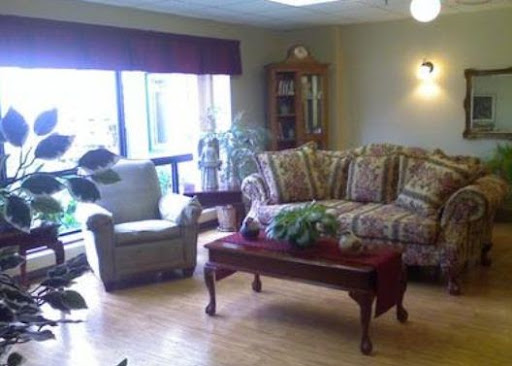 A cozy living room setup featuring a floral sofa, an armchair, and a wooden coffee table adorned with plants.