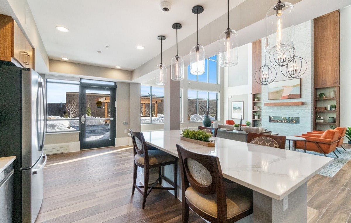 A modern kitchen and dining area featuring sleek countertops, pendant lighting, and stylish bar stools.