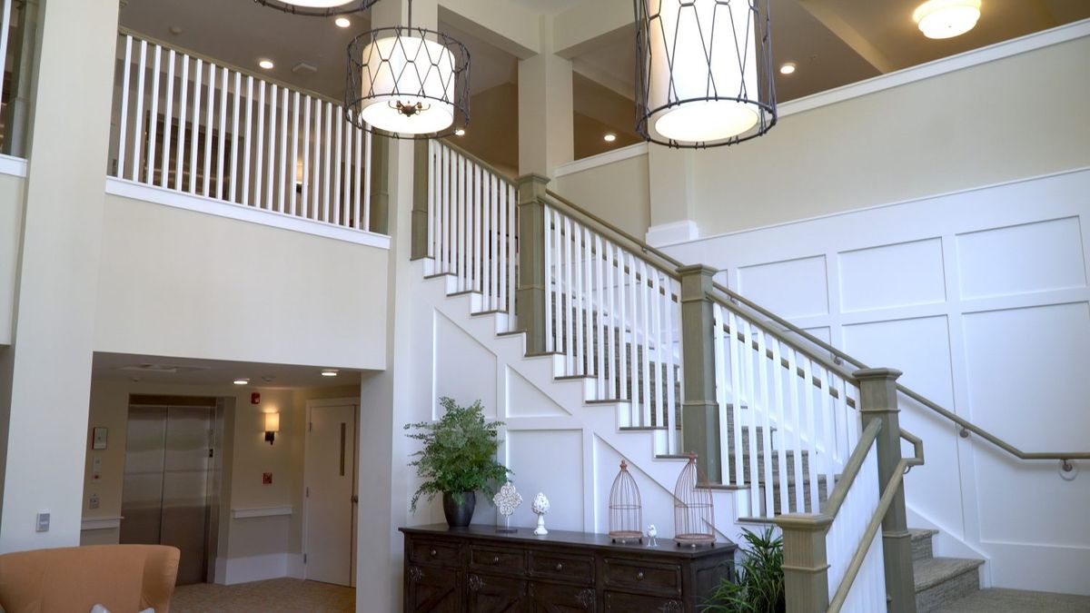 A modern interior featuring a staircase with elegant chandeliers and white railings.