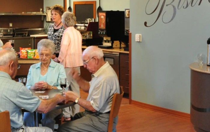 A group of seniors playing cards and socializing in a cafe setting.