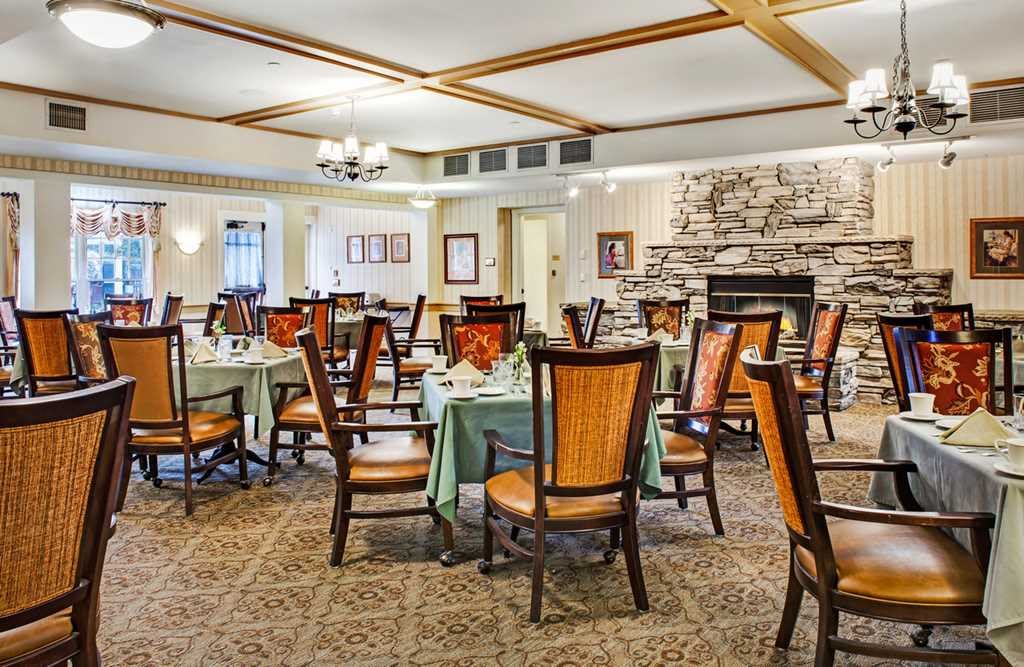 A cozy dining room with elegantly set tables and a stone fireplace.