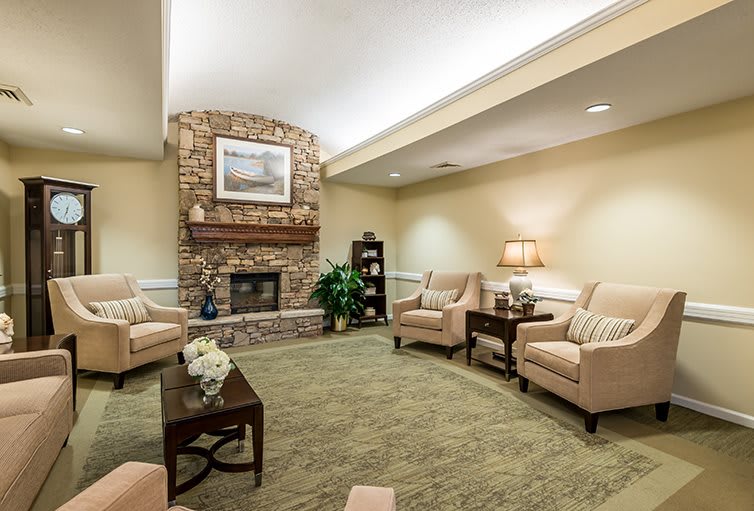 A cozy living room with a stone fireplace, comfortable seating, and warm lighting.