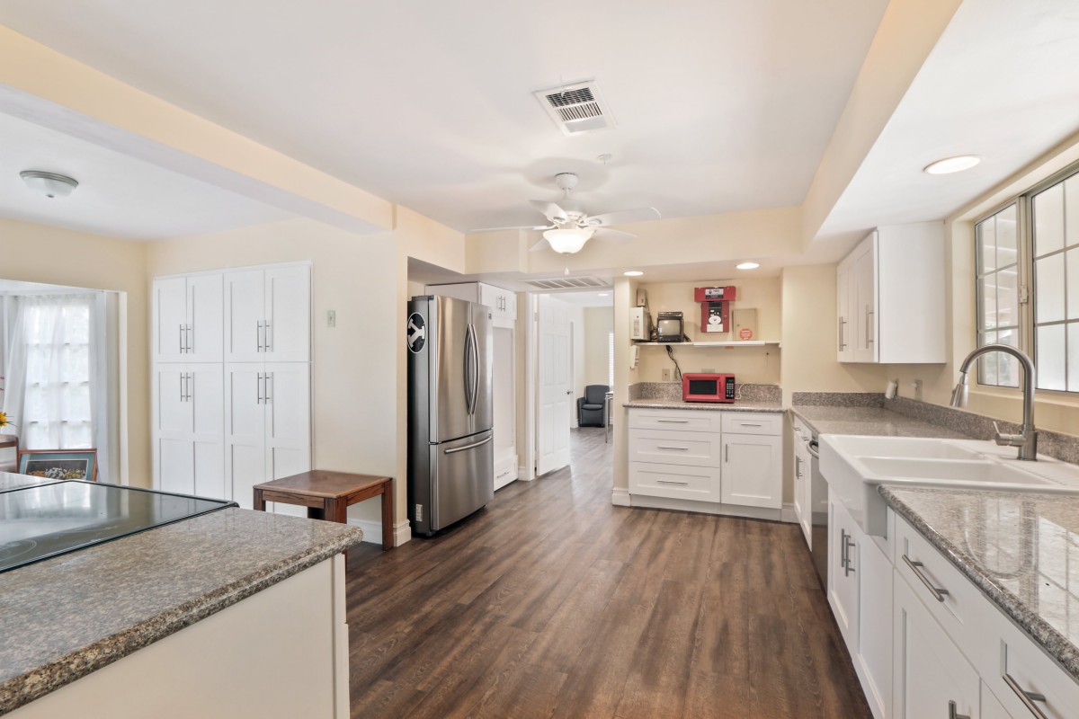 A modern kitchen with white cabinets, stainless steel appliances, and wood flooring.
