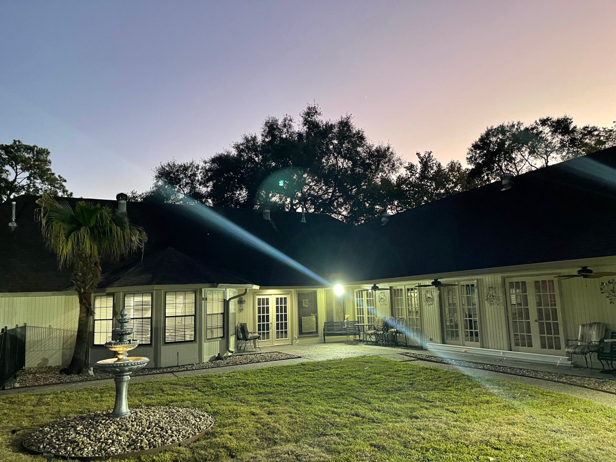 A serene evening view of a house with exterior lights illuminating the yard.