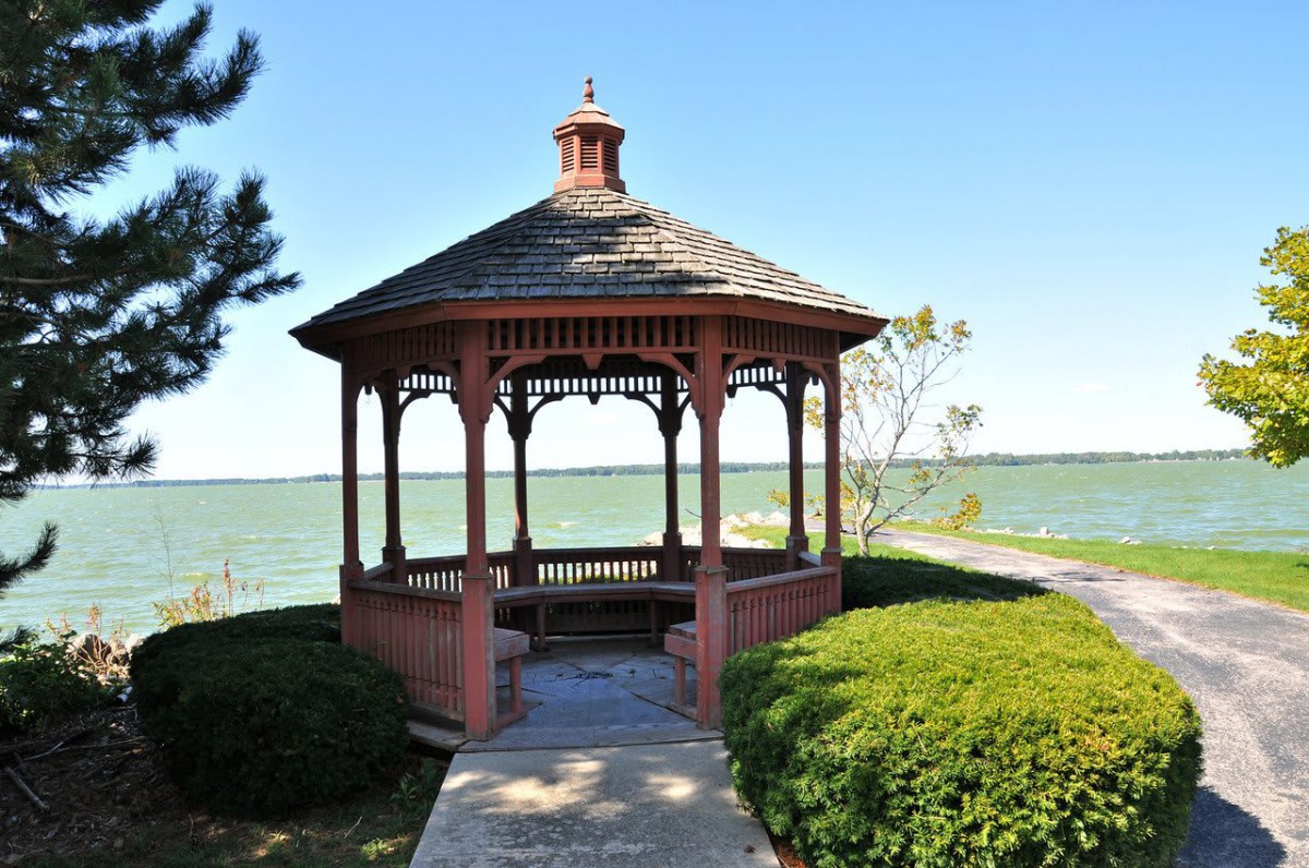 A picturesque gazebo overlooking a serene lake, surrounded by lush greenery.