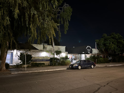 A quiet street at night with a parked car in front of a residential house.