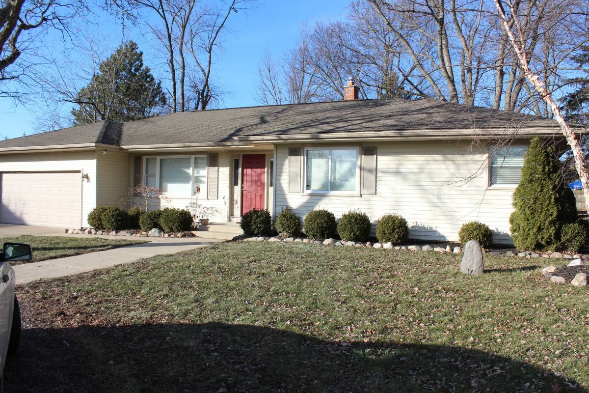 A suburban ranch-style house with a front yard and driveway.