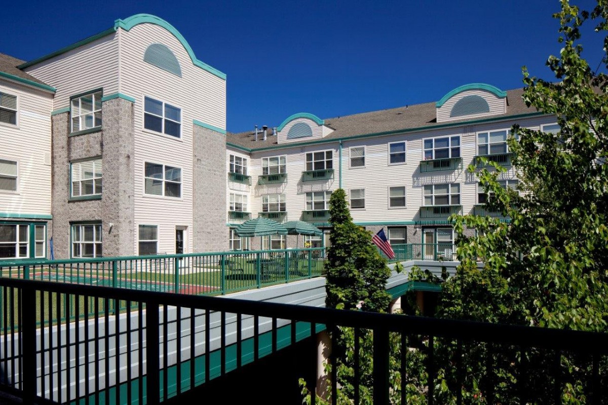 A multi-story residential building with balconies and clear blue skies in the background.