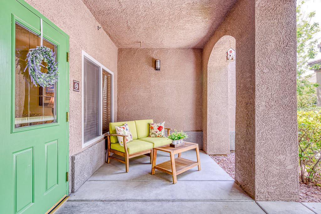 A cozy patio with a green door featuring comfortable seating and a small table.