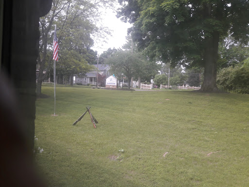 A peaceful park scene featuring a flag, grassy area, and surrounding trees.