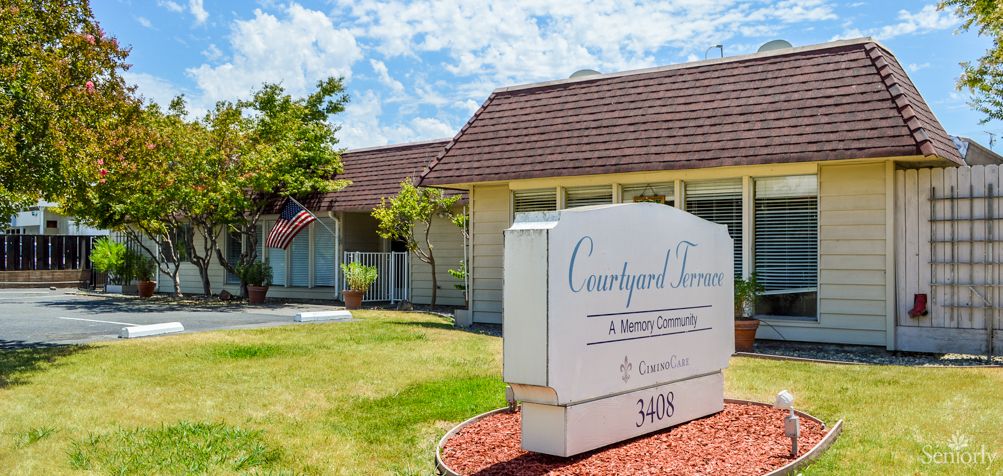 A residential building with a lawn and a prominent sign reading 'Courtyard Terrace' under a clear sky.