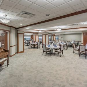 An elegant dining area with neatly arranged tables and chairs, featuring a carpeted floor and soft lighting.